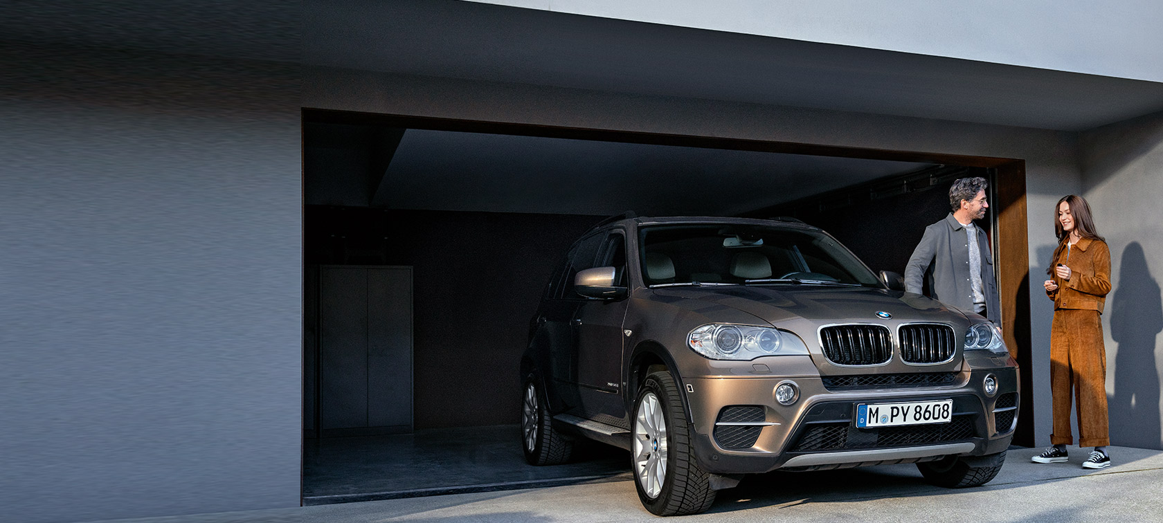 Programa BMW Fidelidade, um homem e uma mulher em frente a uma garagem com o BMW X5